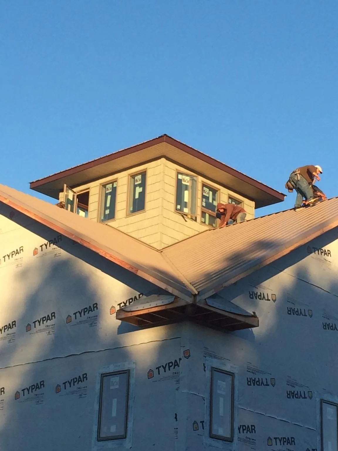 Roofers working around a rooftop cupola on a new metal roof at sunset — Roof Waterproofing in Liberty by Roofing Brothers